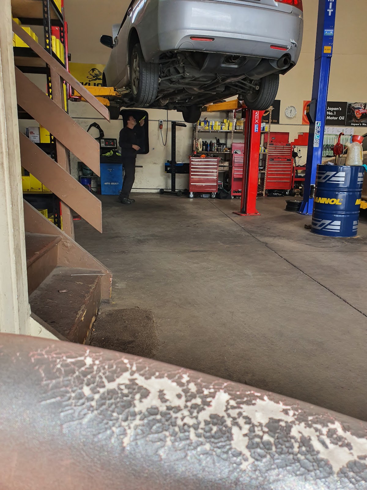 A mechanic at work under a car at Kiwi Motor Services
